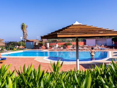 Outdoor pool with umbrellas, people relaxing.