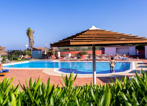 Outdoor pool with umbrellas, people relaxing.